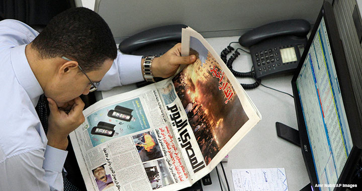 Mideast Egypt Economy An Egyptian trader reads a local newspaper, which features coverage of clashes between protesters and security forces, at the Egyptian stock exchange in Cairo on 20 November 2011.