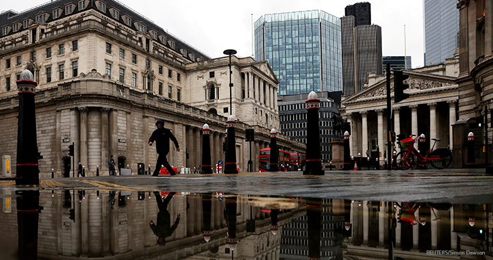 The Bank of England and Royal Exchange are reflected in a puddle as a pedestrian walks past, amid the coronavirus outbreak in London.
