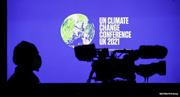 A cameraman sits in front of a screen displaying the COP26 logo during a news conference at the UN Climate Change Conference in Glasgow, Scotland, 5 November 2021.