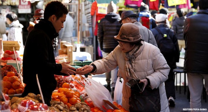 A woman pays money as she buys fruits outside a vegetable store at Ameyoko shopping district in Tokyo, Japan.