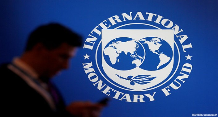 A participant stands near a logo of IMF at the International Monetary Fund – World Bank Annual Meeting 2018 in Nusa Dua, Bali, Indonesia, 12 October 2018.