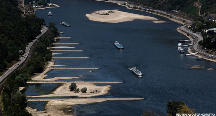 Transport vessels cruise past the partially dried riverbed of the Rhine river in Bingen, Germany, 9 August 2022.
