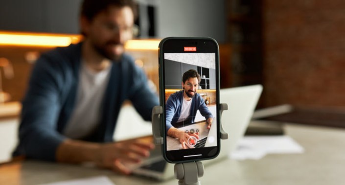Man recording cell phone video of himself at computer.